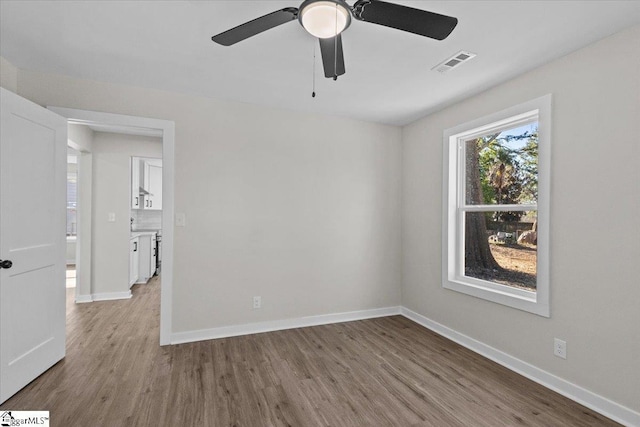 spare room with wood finished floors, visible vents, and baseboards