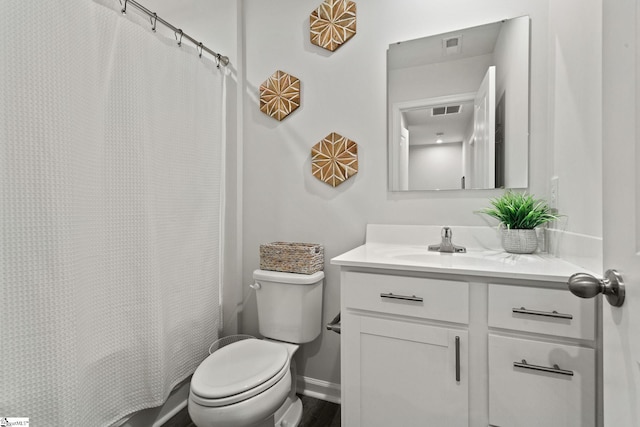 full bath featuring toilet, vanity, visible vents, and baseboards