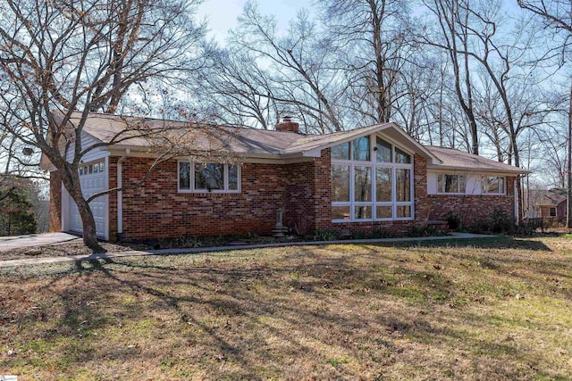 view of front of property featuring brick siding, a chimney, an attached garage, and a front yard