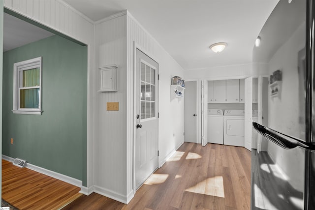 hall featuring washer and clothes dryer, wood finished floors, visible vents, and baseboards