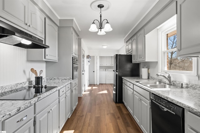 kitchen with under cabinet range hood, separate washer and dryer, dark wood-style flooring, a sink, and black appliances