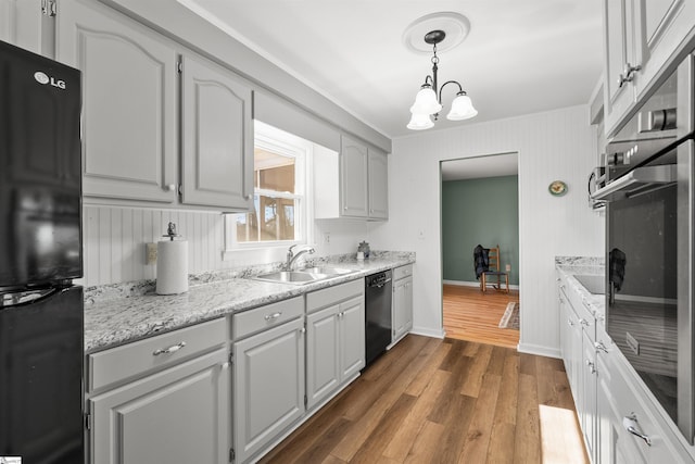 kitchen featuring dark wood finished floors, a notable chandelier, a sink, black appliances, and baseboards