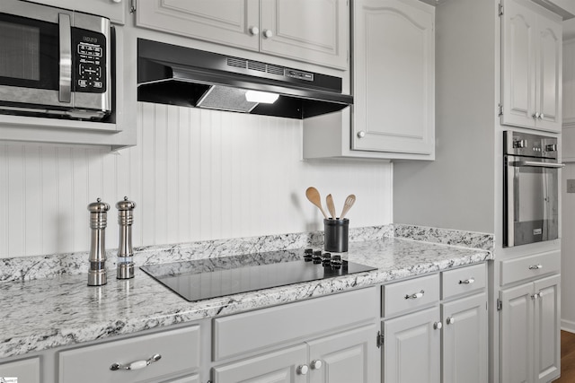 kitchen with appliances with stainless steel finishes, light stone countertops, white cabinetry, and under cabinet range hood