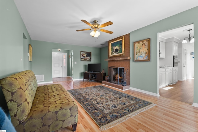 living room featuring visible vents, a fireplace, baseboards, and wood finished floors