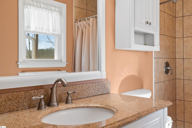 full bathroom featuring tiled shower and vanity