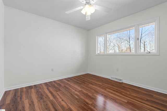 spare room with dark wood-style floors, baseboards, visible vents, and a ceiling fan