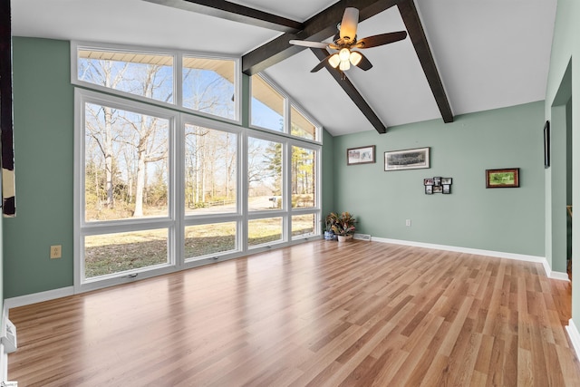 unfurnished living room featuring a ceiling fan, baseboards, vaulted ceiling with beams, and light wood finished floors