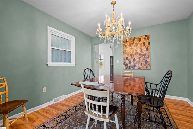 dining space with a chandelier, visible vents, baseboards, and wood finished floors