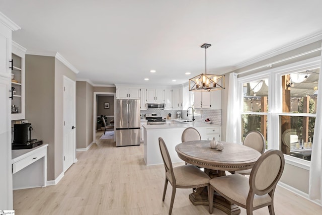 dining room with light wood finished floors, baseboards, a chandelier, and crown molding