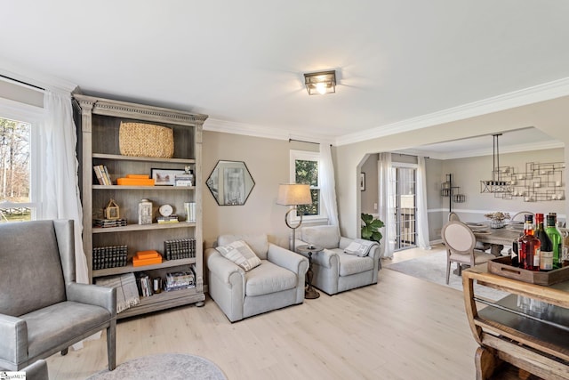 living area with light wood-type flooring, plenty of natural light, and ornamental molding