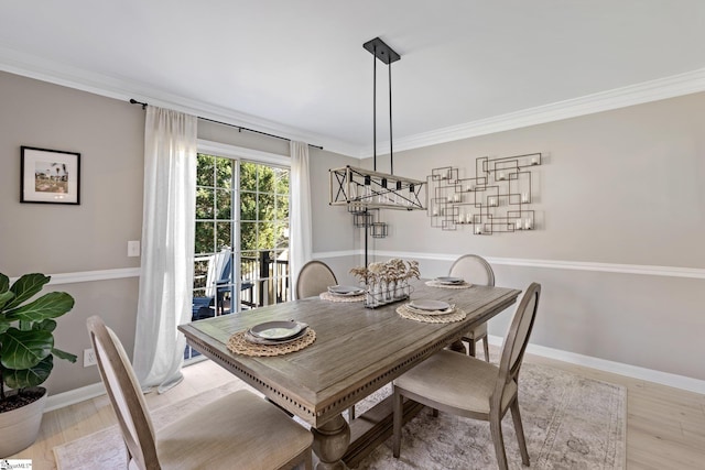 dining room featuring light wood-style floors, baseboards, and crown molding