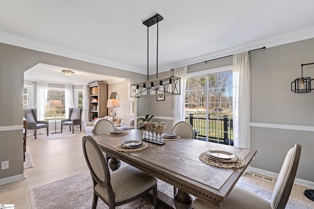 dining area featuring crown molding, baseboards, visible vents, and light wood-style floors