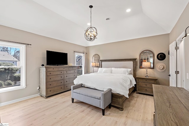 bedroom featuring light wood finished floors, baseboards, a raised ceiling, lofted ceiling, and an inviting chandelier