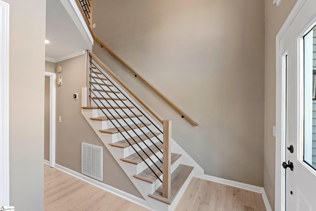 staircase with visible vents, baseboards, and wood finished floors