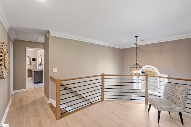 hall with a notable chandelier, crown molding, attic access, an upstairs landing, and wood finished floors