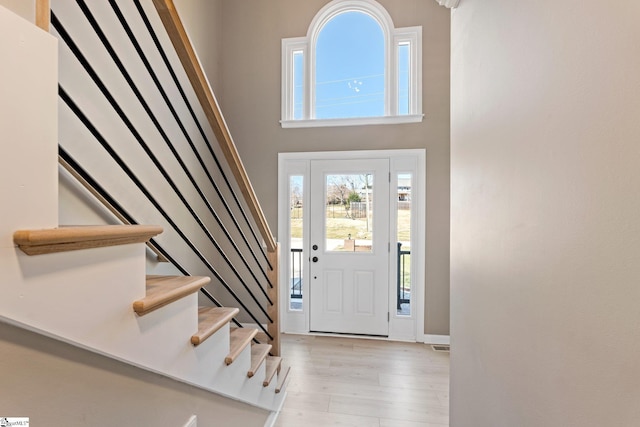 entryway featuring stairs, a high ceiling, and wood finished floors