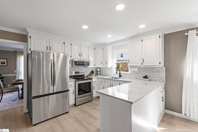 kitchen with white cabinets, appliances with stainless steel finishes, a peninsula, crown molding, and a sink