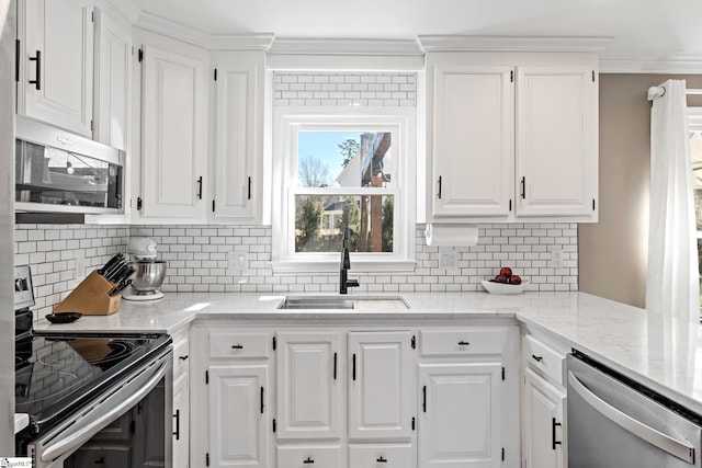 kitchen with appliances with stainless steel finishes, backsplash, a sink, and white cabinets