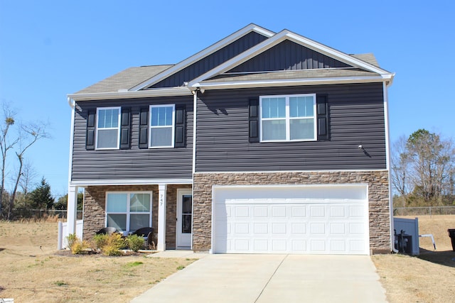 view of front facade featuring an attached garage, fence, concrete driveway, stone siding, and board and batten siding