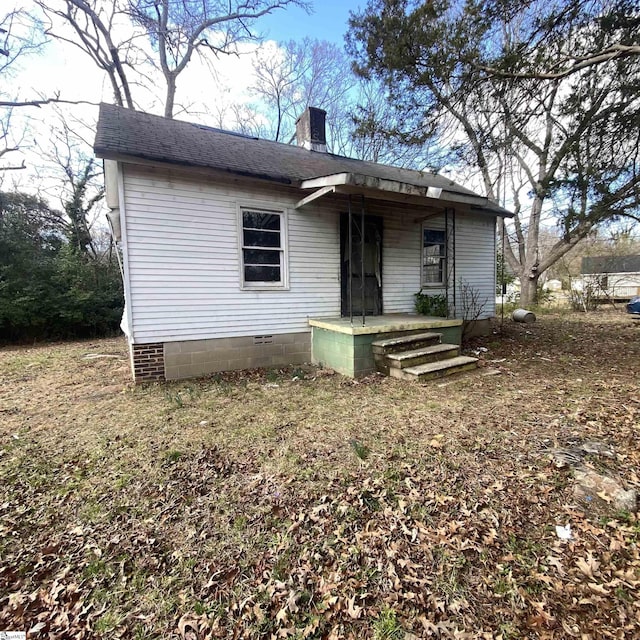 view of front of home with crawl space, roof with shingles, and a chimney