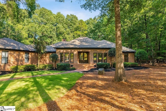 view of front facade with a front lawn, crawl space, a chimney, and brick siding