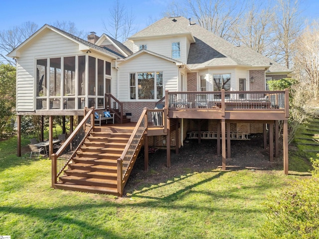 rear view of house featuring a chimney, a lawn, stairway, a sunroom, and a wooden deck