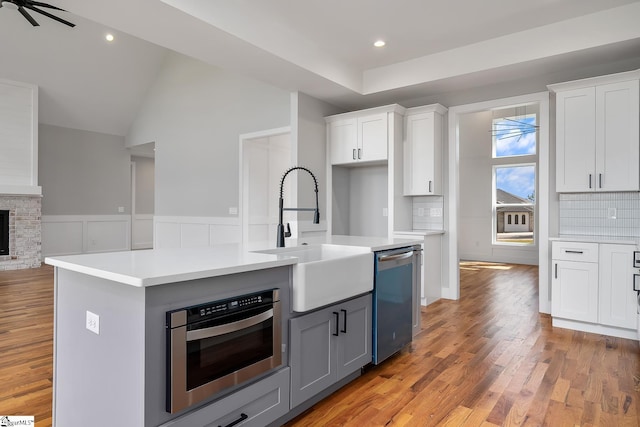 kitchen with dishwasher, a brick fireplace, a sink, and white cabinets