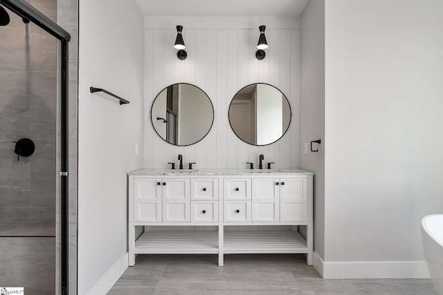 bathroom featuring a stall shower, baseboards, a sink, and a freestanding bath