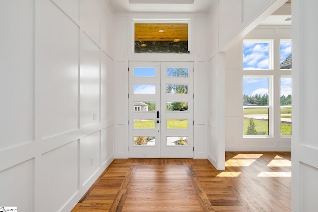 doorway with french doors, light wood finished floors, and a decorative wall