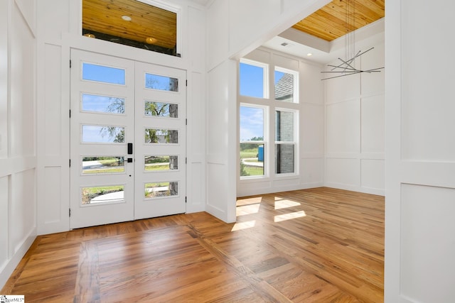 entrance foyer with light wood-style floors, plenty of natural light, a decorative wall, and a towering ceiling