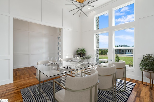 dining area featuring a high ceiling, wood finished floors, and a decorative wall