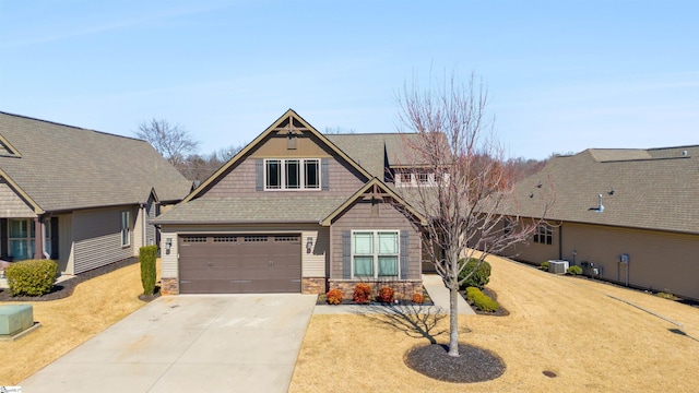 craftsman inspired home with roof with shingles, central air condition unit, a garage, stone siding, and driveway