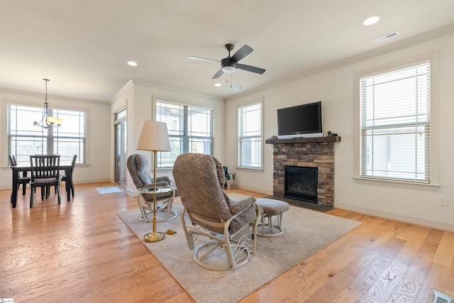 living room with light wood-type flooring, a healthy amount of sunlight, visible vents, and ornamental molding