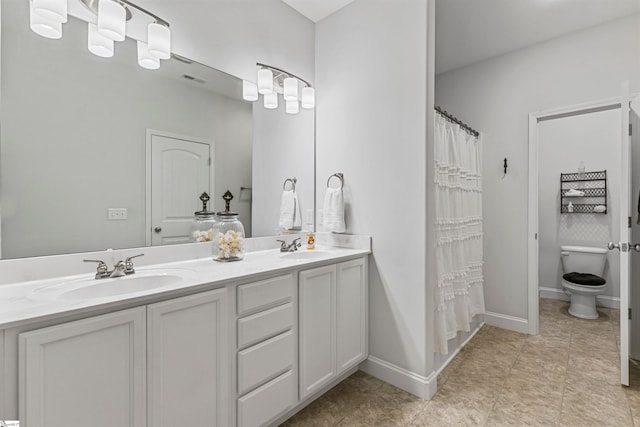 full bathroom with baseboards, a sink, toilet, and double vanity