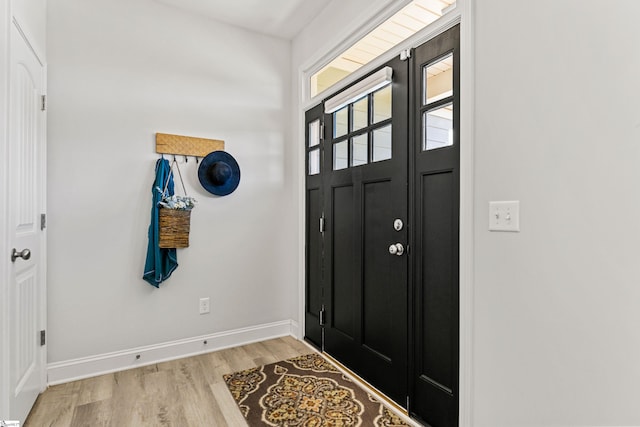 foyer entrance with light wood-style floors and baseboards