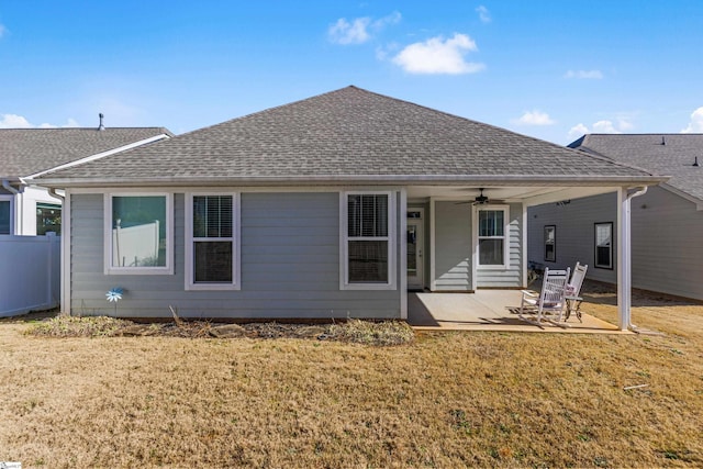 back of property featuring a ceiling fan, a patio area, roof with shingles, and a lawn