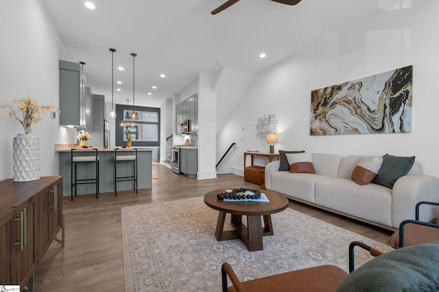 living room featuring lofted ceiling, a ceiling fan, light wood-style flooring, and recessed lighting