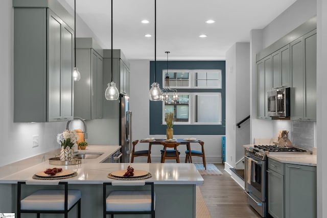 kitchen with appliances with stainless steel finishes, a breakfast bar, light countertops, and tasteful backsplash