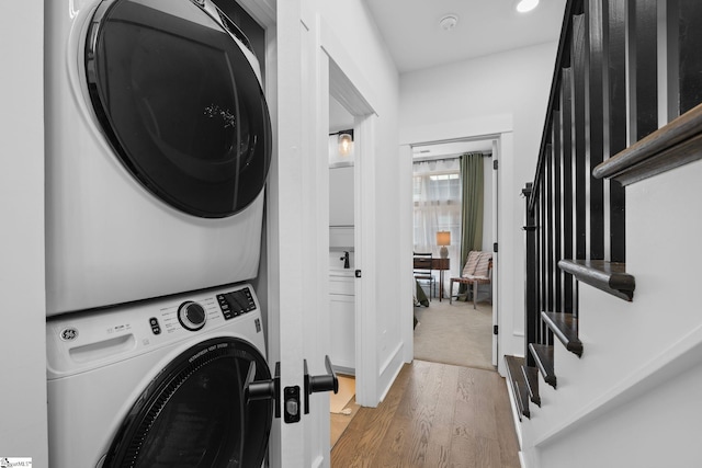 laundry room featuring wood finished floors and stacked washer / drying machine