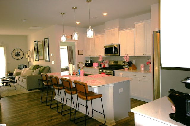 kitchen featuring dark wood-style floors, a breakfast bar, stainless steel appliances, white cabinetry, and a sink