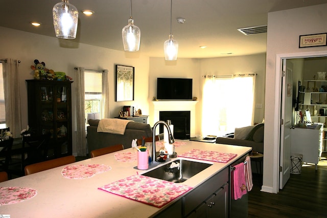 kitchen with visible vents, open floor plan, light countertops, a fireplace, and a sink