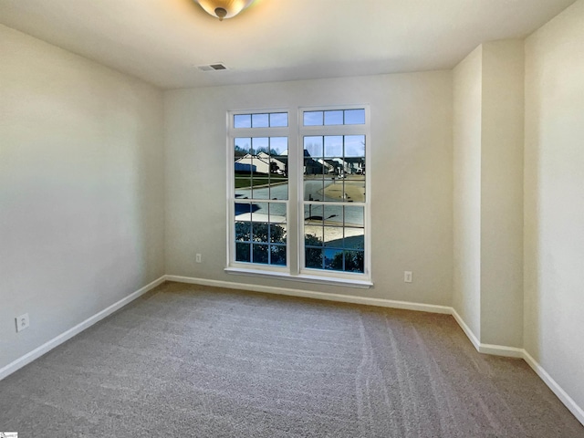 spare room featuring carpet, visible vents, and baseboards