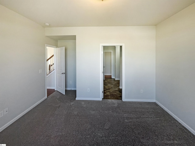 unfurnished bedroom with dark carpet and baseboards