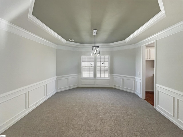 carpeted spare room featuring visible vents, a raised ceiling, crown molding, and a decorative wall