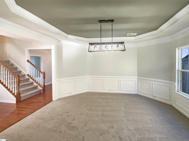 empty room with stairs, carpet floors, a tray ceiling, and visible vents