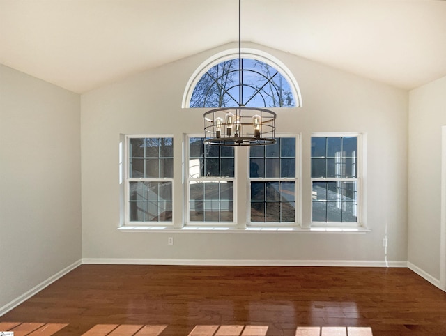 unfurnished dining area featuring baseboards, vaulted ceiling, a notable chandelier, and wood finished floors