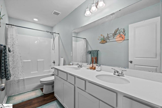 bathroom with double vanity, visible vents, toilet, and a sink