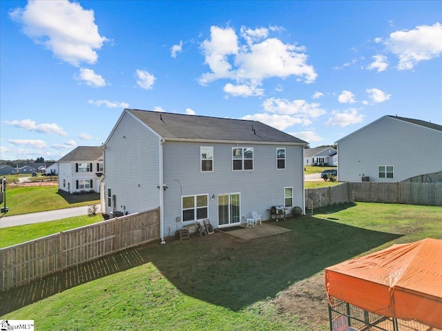 rear view of house with a residential view, a fenced backyard, and a yard