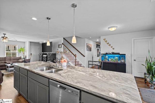 kitchen featuring light stone counters, open floor plan, a sink, wood finished floors, and dishwasher