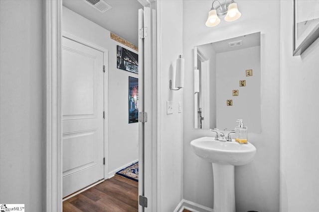 bathroom with a sink, wood finished floors, visible vents, and an inviting chandelier